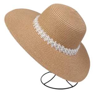 Close-up of wide brim straw hat with white lace trim and pearl detailing on stand