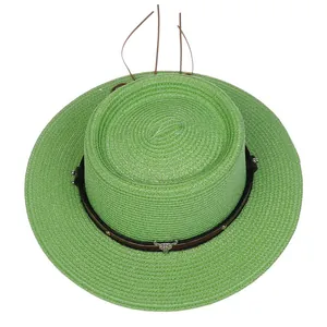 Detail eines grünen Strohhuts mit braunem Lederband und silbernem Stierkopf-Accessoire