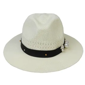 Detailed weave of cream fedora hat featuring black band with pearls and metal studs