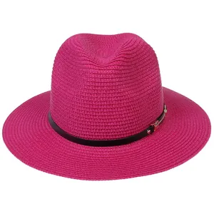 Détail du chapeau de paille Panama rose avec bande en cuir noir et boucle dorée