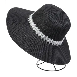 Detail of black straw sun hat with elegant white floral and faux pearl trim