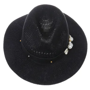 Close-up of black woven sun hat with elegant pearl and gold bead ribbon decoration