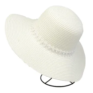 Detail of woven straw sun hat with elegant pearl and white lace ribbon decoration