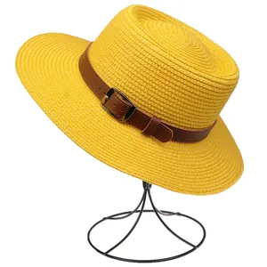 Detail of yellow straw hat featuring a brown faux leather band and silver metal buckle