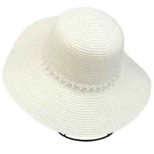 Close-up of wide-brim straw sun hat with delicate pearl lace trim on white background