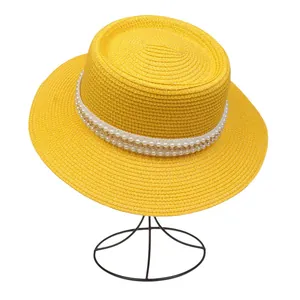 Detailansicht gelber Strohhut mit eleganten Perlen und goldener Kette am Band