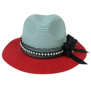 Detail of mint green and red straw hat with black lace, pearls and a large silk bow