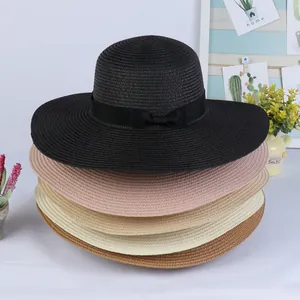 Detail view of woven straw sun hats in multiple colors with black ribbon bows