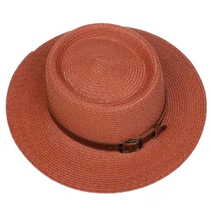 Detail of brick red woven boater hat with a dark brown leather belt and metal buckle