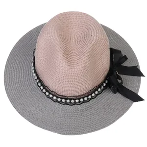 Detail of two-tone woven straw hat with black lace, white pearls and a silk bow