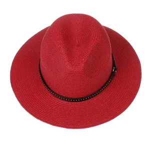 Detail of red fedora straw hat featuring a black leather band with golden metal rivets