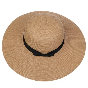 Detailed view of the woven straw texture and elegant black ribbon bow on a wide brim sun hat