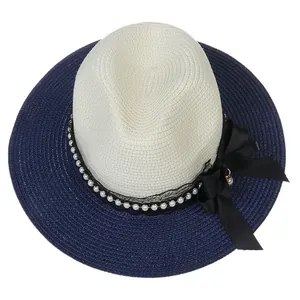 Detail of Panama straw hat featuring a navy brim, pearl band, and black ribbon bow