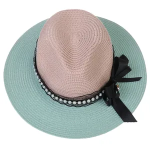 Detail of bicolor straw hat with black lace ribbon, white pearls and a large bow