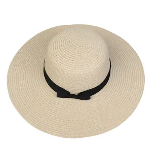 Detail of beige straw beach hat featuring fine weave texture and a black ribbon bow