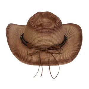 Detalle de sombrero de paja con banda de cuero, remaches plateados y adornos de borlas