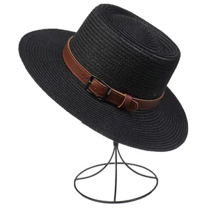 Detail of black woven straw hat featuring brown leather band and metallic buckle accent