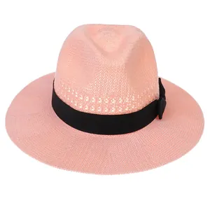 Close-up of the breathable woven texture and black ribbon bow on a pink straw fedora