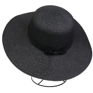Detail of black wide brim straw hat featuring elegant woven texture and ribbon bow