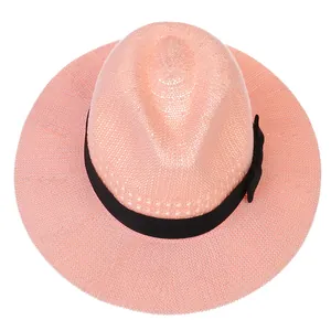 Detail of light pink summer straw fedora hat with elegant black ribbon and side bow tie