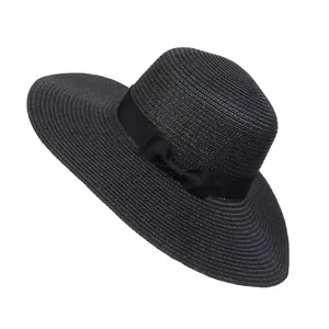 Detail of black straw beach hat featuring wide brim and elegant side ribbon bow