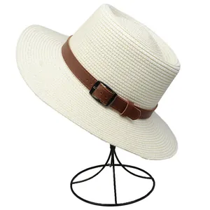 Close-up of woven straw hat texture with brown leather band and metallic buckle detail