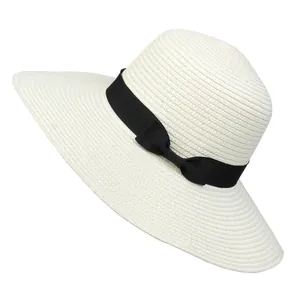 Close-up of woven straw sun hat with wide brim and black grosgrain ribbon bow