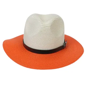 Detail of two-tone woven straw hat with orange brim and leather band with silver buckle