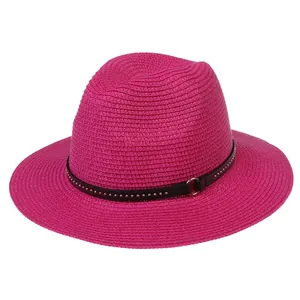 Detail of rose red woven straw fedora featuring a black studded band with gold buckle