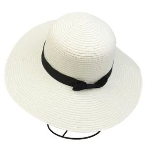 Close-up of a wide-brim straw sun hat in beige with a black ribbon bow detail