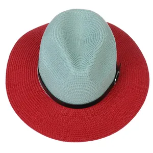 Detail of red and mint green panama straw hat with a black leather band and metal buckle