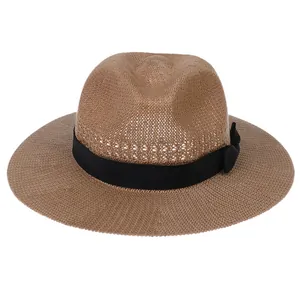 Close-up of brown straw fedora featuring a wide black ribbon and textured weave