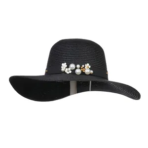 Detail of woven straw sun hat featuring white pearl beads and floral embellishments
