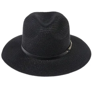 Détail d'un chapeau Panama en paille noire avec texture tressée et boucle dorée élégante
