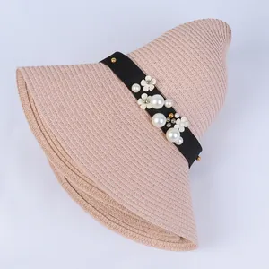Close-up of pink wide-brim straw hat featuring black band with pearls and floral details
