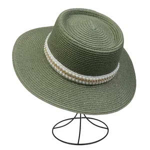 Nahaufnahme grüner Strohhut mit eleganten weißen Perlen und goldener Kette als Detail