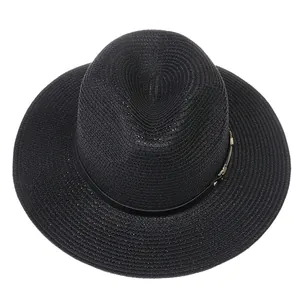 Détail du chapeau de paille noir avec texture tressée et boucle en métal doré élégante