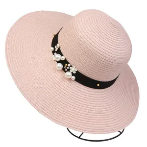 Detail of pink woven straw sun hat with pearl accents and flower ribbon decoration
