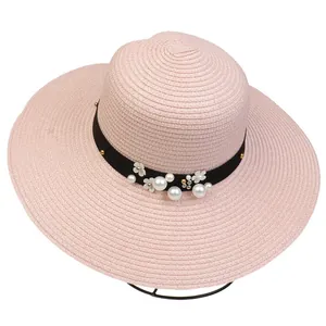 Detail of pink straw sun hat featuring elegant pearls, white flowers and black ribbon