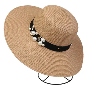 Macro detail of khaki woven straw hat with pearl floral trim on a metal display stand