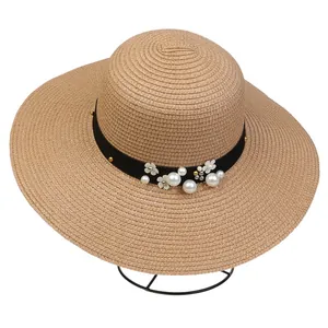 Close-up of wide brim straw sun hat with black ribbon and delicate pearl flower details