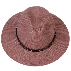Detail of dusty pink straw hat featuring fine weave and brown leather studded band