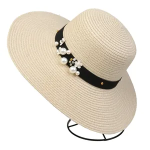 Detail of wide brim straw hat with elegant black ribbon, pearls and floral decorations