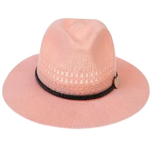 Close-up of pink woven straw hat featuring a black textured band and a heart charm