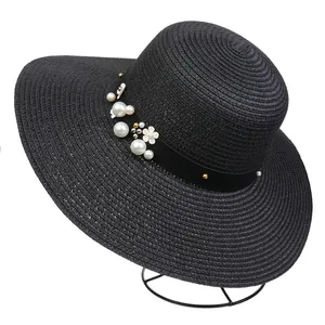 Close-up of black wide brim straw hat featuring white floral and pearl embellishments