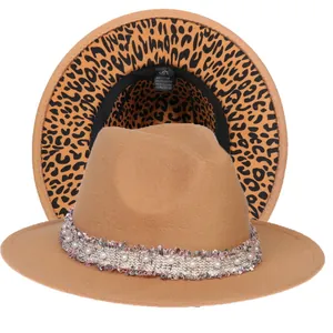 Dettaglio di cappello fedora kaki con tesa leopardata e nastro decorato con perle e nappe