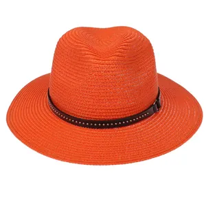 Detailed texture of orange straw Panama hat with black studded leather band