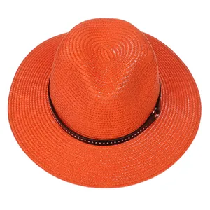 Detail of orange woven straw hat featuring a slim brown leather belt with silver studs