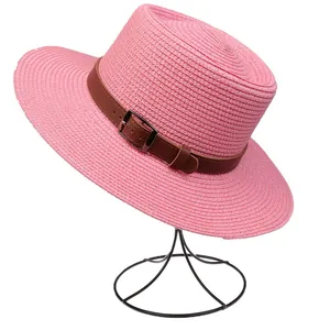 Detail of bright pink straw fedora hat with fine woven texture and brown leather belt