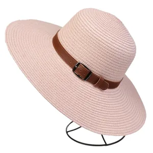 Detail of light pink wide-brim straw hat featuring a brown leather band with buckle